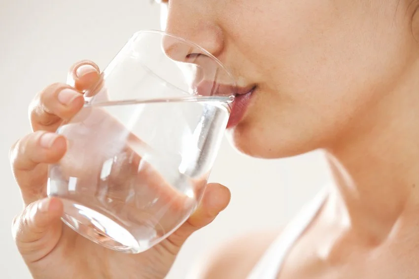 A close up photo of a woman drinking water from a glass